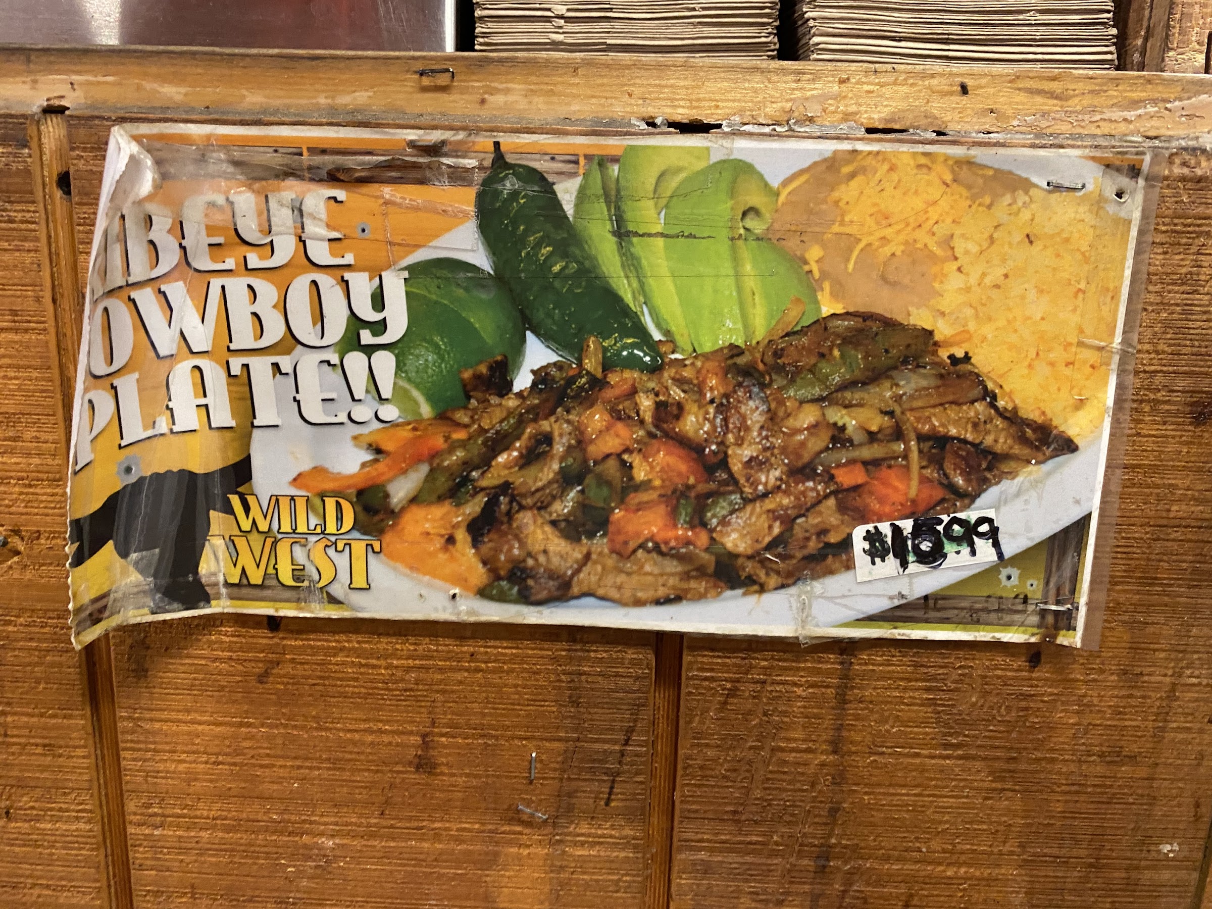 Wild West Cowboy Steakhouse hand-painted Ribeye Cowboy Plate sign showing a loaded grilled steak plate. TODO: client to swap with own steak photo.