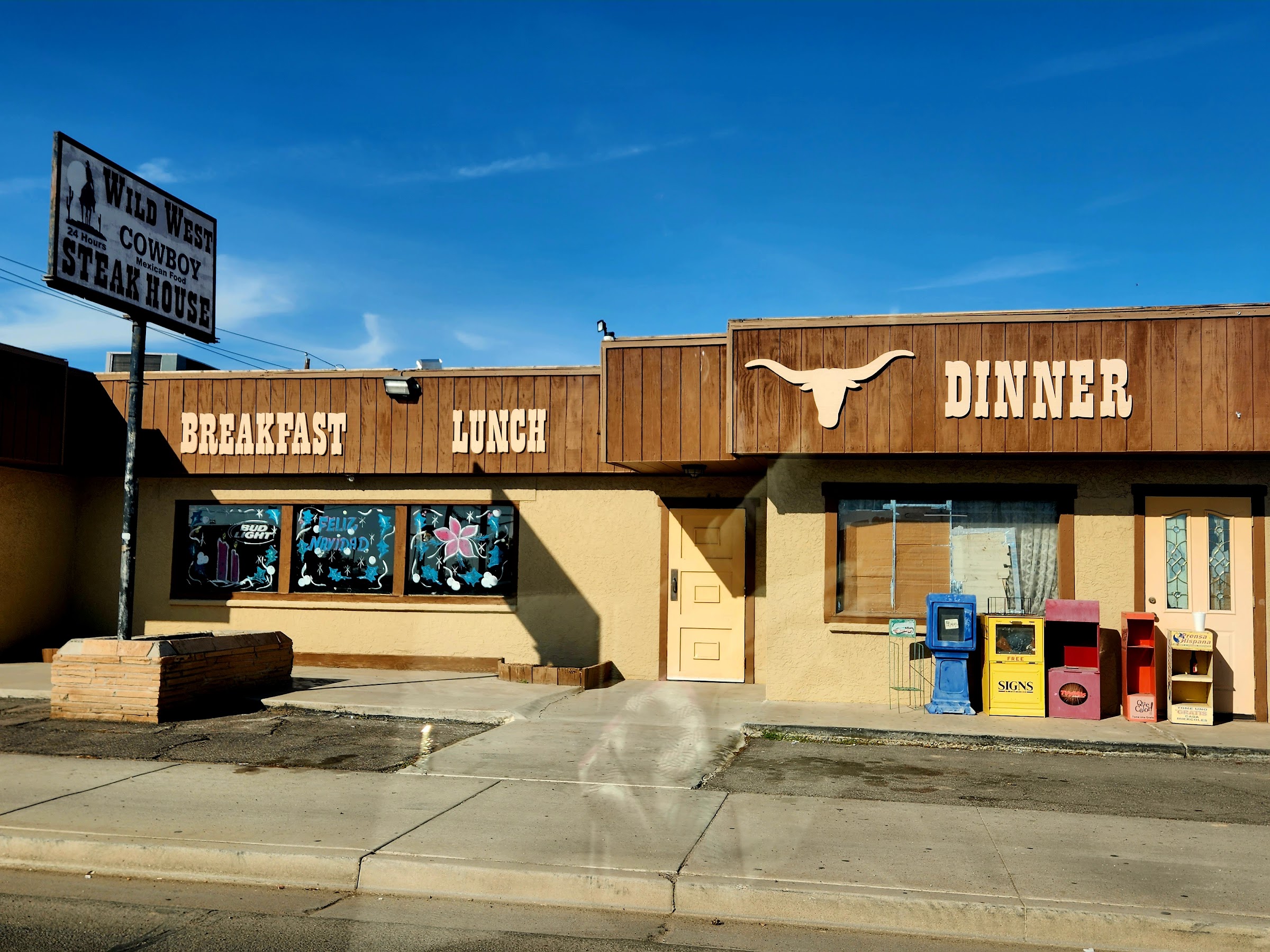 Daytime view of the Wild West Cowboy Steakhouse storefront with the Breakfast, Lunch, Dinner signage and longhorn.